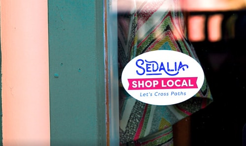 A shop local sticker in the window of a downtown business